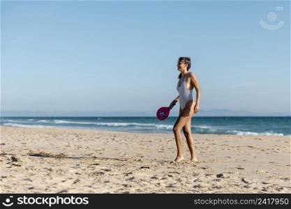 happy young woman playing tennis seashore