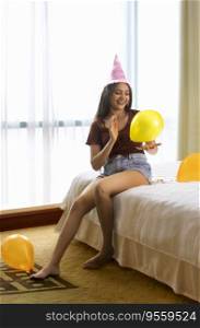 Happy young woman playing with balloons on bed