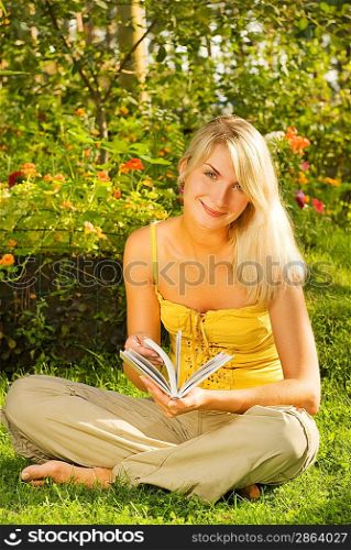 Happy young woman readin book in a park