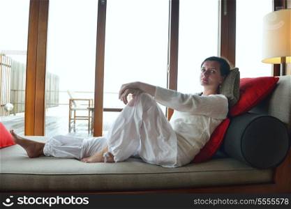 happy young woman relax at home on sofa in bright living room and watching tv