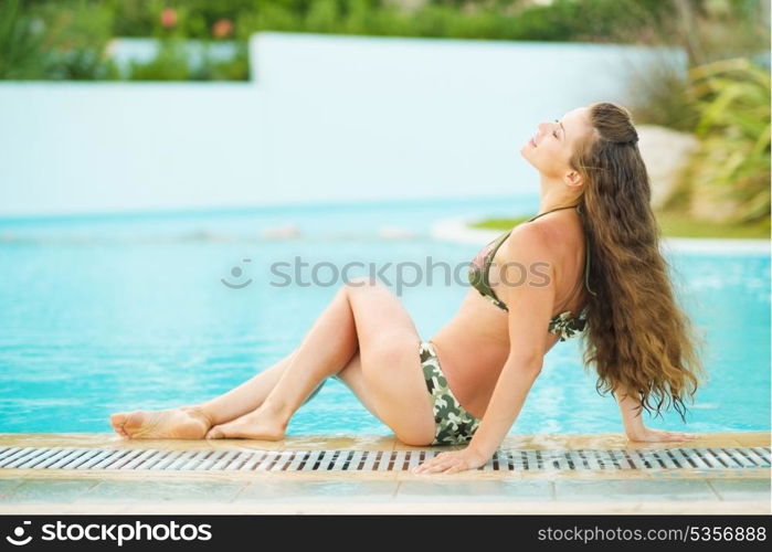 Happy young woman relaxing at poolside
