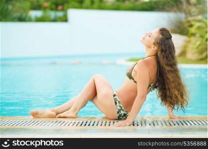 Happy young woman relaxing at poolside