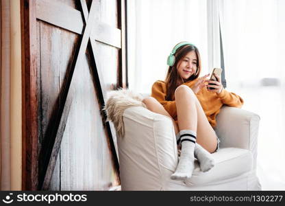 Happy Young Woman Relaxing by Music Headphone from Smartphone on Sofa in Cozy House, Lifestyle of Modern People