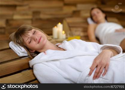 Happy young woman relaxing on wooden chair at luxury spa