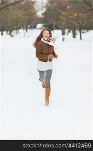 Happy young woman running in winter park