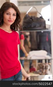 Happy young woman shopping in boutique store - standing near glasscase