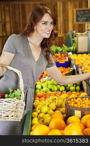 Happy young woman shopping in supermarket for fruits