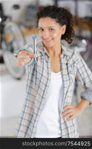 happy young woman showing a spanner while repairing bike
