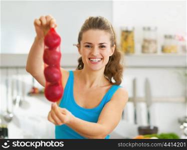 Happy young woman showing bunch of red onions