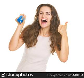 Happy young woman showing keys and thumbs up