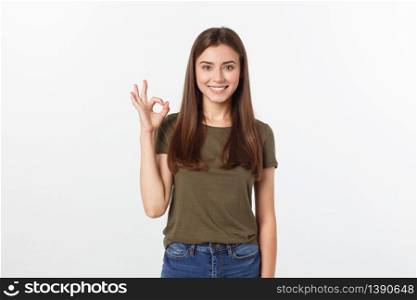 Happy young woman showing ok sign with fingers an winking isolated on a gray background. Happy young woman showing ok sign with fingers an winking isolated on a gray background.