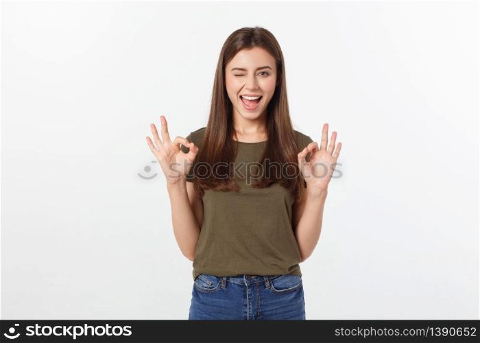 Happy young woman showing ok sign with fingers an winking isolated on a gray background. Happy young woman showing ok sign with fingers an winking isolated on a gray background.