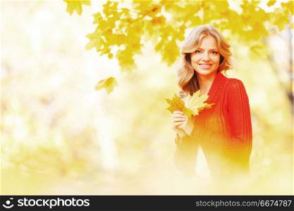 Happy young woman sitting on autumn leaves in park. Woman sitting on autumn leaves
