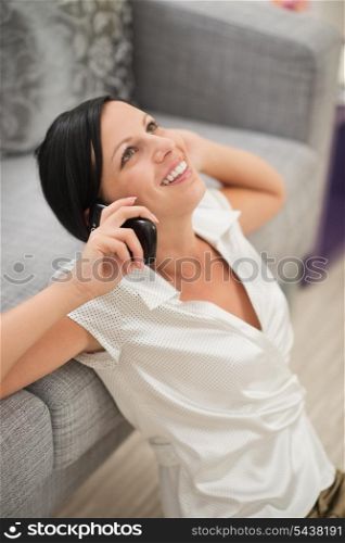 Happy young woman sitting on floor and talking mobile phone