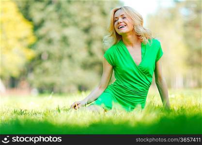 Happy young woman sitting on grass