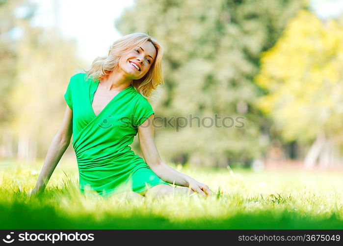 Happy young woman sitting on grass