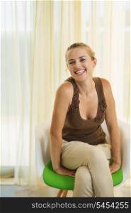 Happy young woman sitting on modern chair