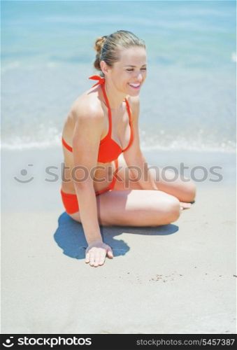Happy young woman sitting on sea shore