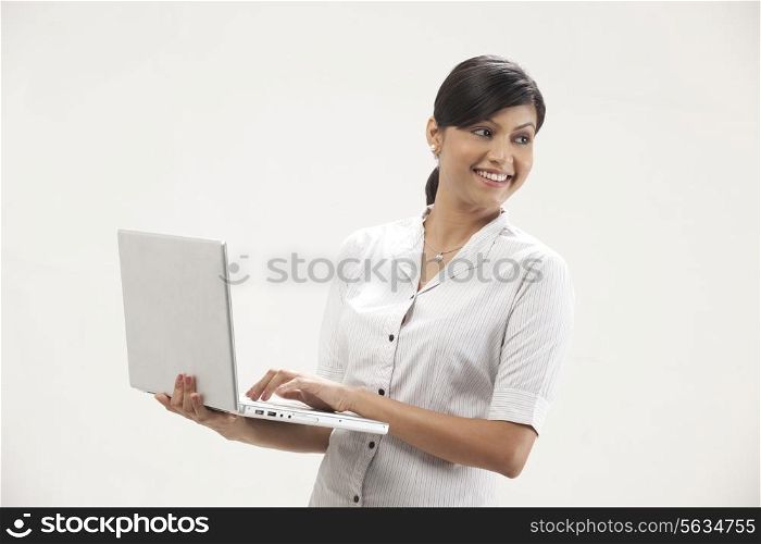 Happy young woman smiling while using laptop