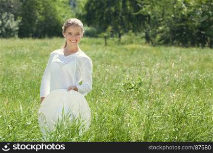 Happy Young Woman Standing with a White Hat at the Green Summer Meadow.