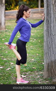 Happy young woman stretching before running outdoors. Runner girl in an urban park.