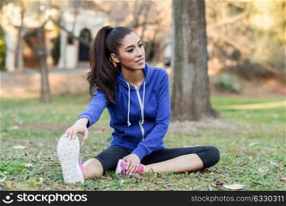 Happy young woman stretching before running outdoors. Runner girl in an urban park.