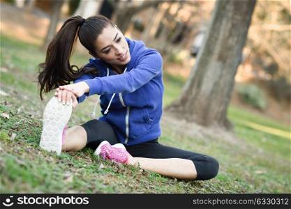 Happy young woman stretching before running outdoors. Runner girl in an urban park.