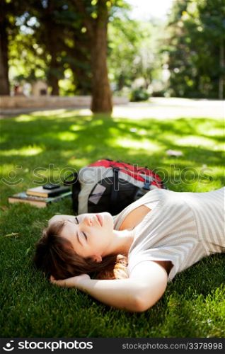 Happy young woman student laying on grass and dreaming about future