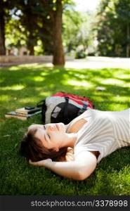Happy young woman student laying on grass and dreaming about future