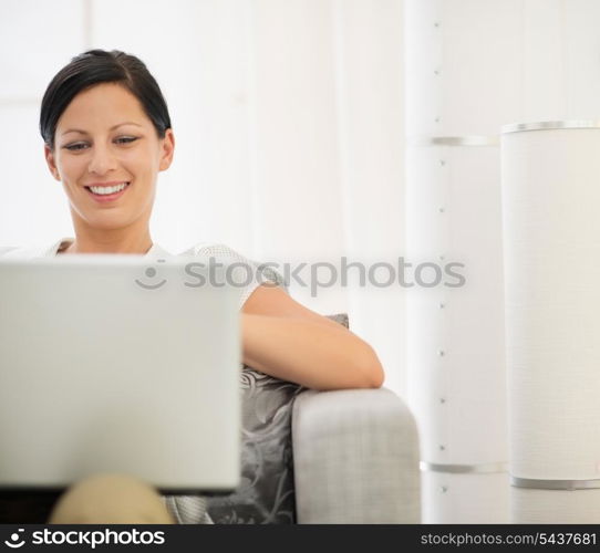 Happy young woman surfing net on laptop