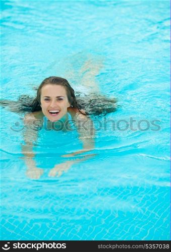 Happy young woman swimming in pool