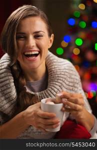 Happy young woman taking out marshmallow from cup of hot chocolate