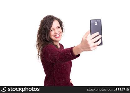 Happy young woman taking self portrait photography through smart phone over white background.