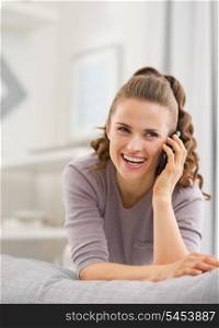 Happy young woman talking mobile phone in living room