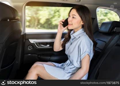 happy young woman talking on mobile phone while sitting in the back seat of car