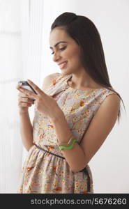 Happy young woman text messaging by window