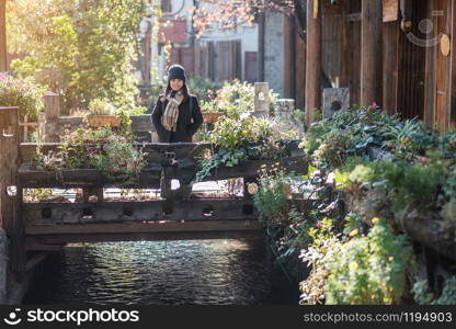 Happy young woman traveler traveling at the Square street in Lijiang Old Town, landmark and popular spot for tourists attractions in Lijiang, Yunnan, China. Asia travel concept