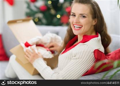 Happy young woman unpacking parcel with Christmas gift