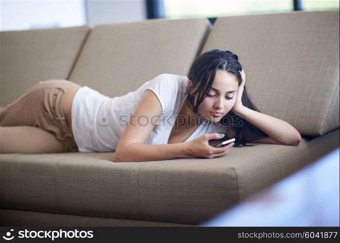 happy young woman using cellphone at home and relaxing