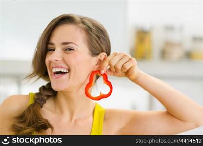 Happy young woman using slice of bell pepper as earring