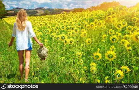Happy young woman walking in fresh sunflowers field, agricultural landscape, autumnal nature, harvest season concept