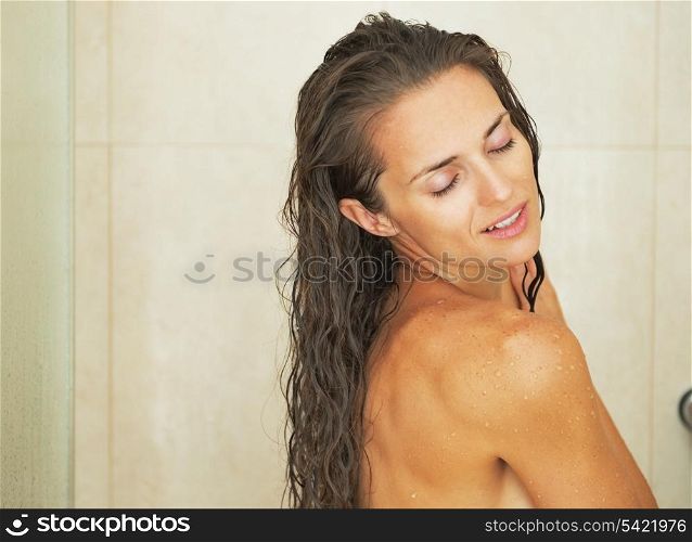Happy young woman washing in shower