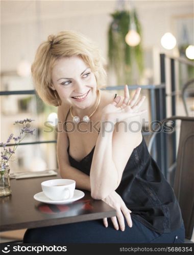 Happy young woman waving at restaurant table