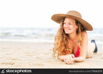 Happy young woman wearing bikini lying on tropical sand beach in summer for holiday travel vacation.. Happy young woman at beach in summer vacation.