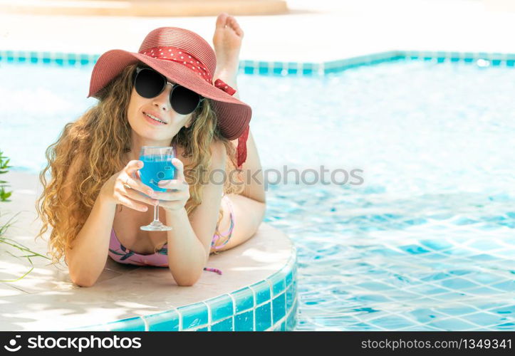 Happy young woman wearing swimsuit having good time at swimming pool in luxury resort. Summer travel holiday concept.