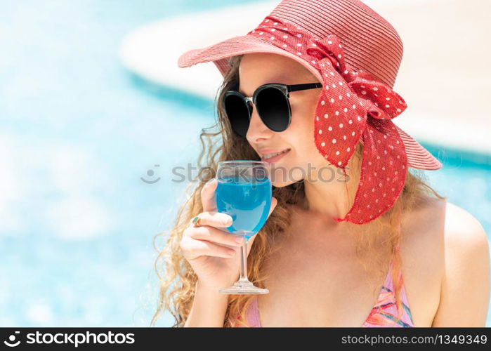 Happy young woman wearing swimsuit having good time at swimming pool in luxury resort. Summer travel holiday concept.