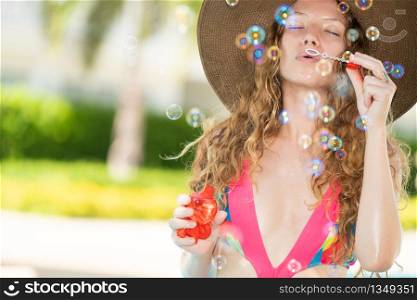 Happy young woman wearing swimsuit having good time at swimming pool in luxury resort. Summer travel holiday concept.