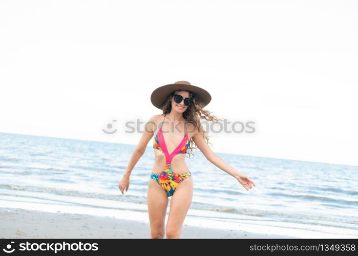 Happy young woman wearing swimsuit having good time at tropical beach in summer for holiday travel vacation.