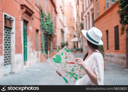 Happy young woman with a city map on italian old street in Europe. Travel tourist woman with map in Rome outdoors during holidays in Italy.. Travel tourist woman with map in Prague outdoors during holidays in Europe.