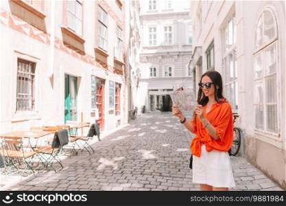 Happy young woman with a city map. Travel tourist girl with map of Vienna outdoors during holidays in Europe.. Young woman with a city map in city. Travel tourist girl with map in Vienna outdoors during holidays in Europe.
